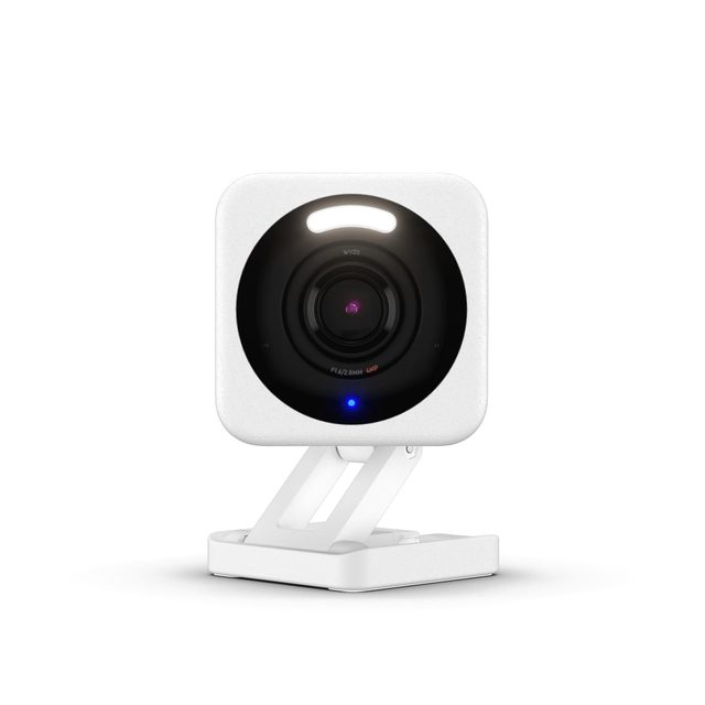 The small white Wyze Cam v4 camera on its round stand